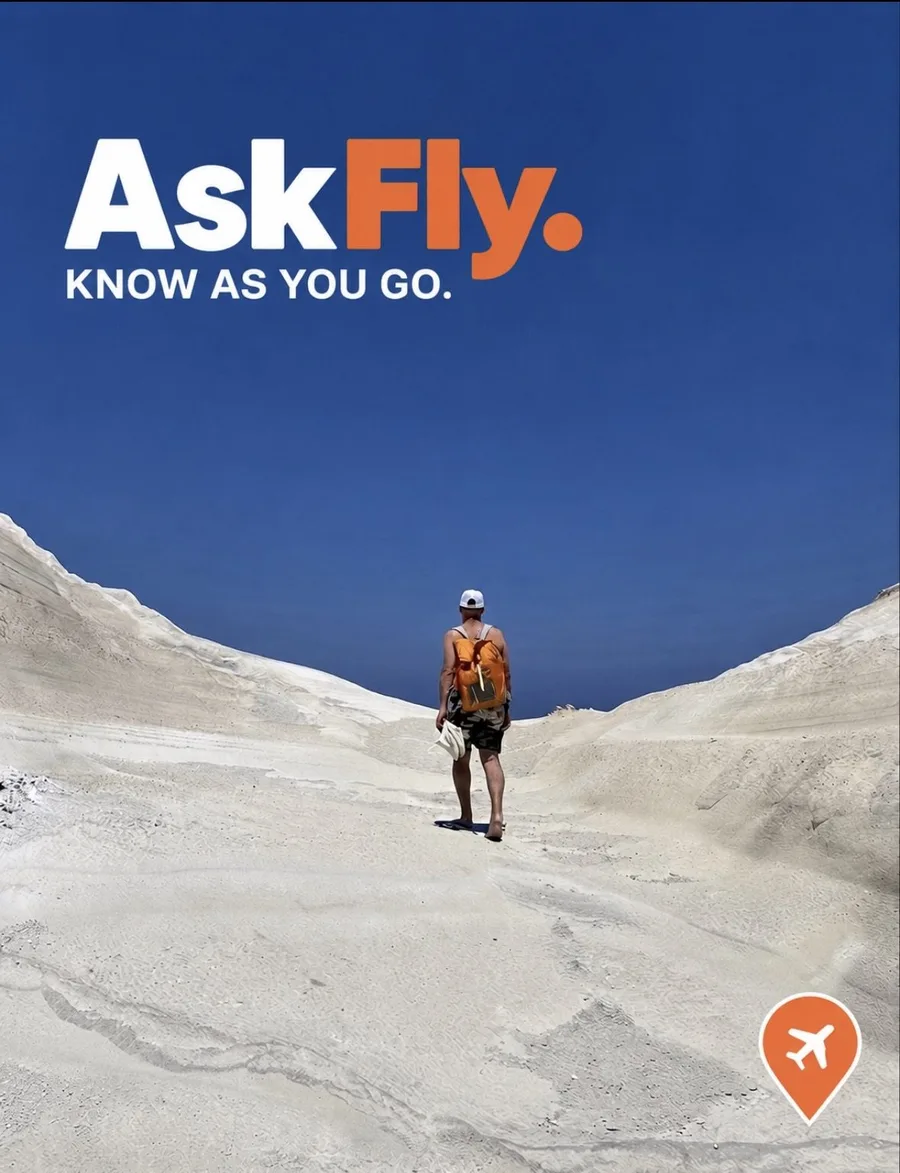 A traveler with an orange backpack walking through white desert hills under a deep blue sky, with the AskFly logo and Know As You Go tagline